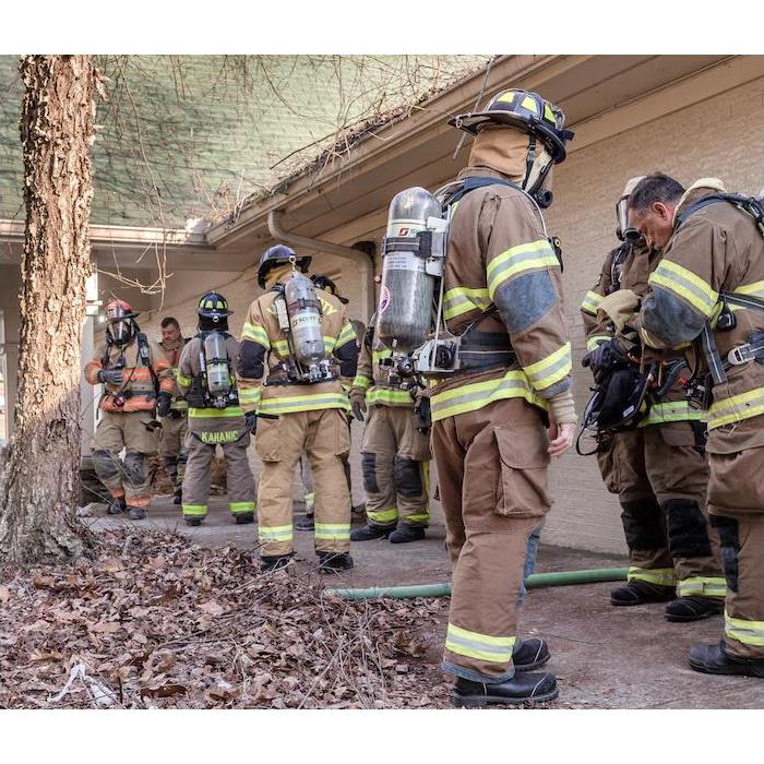 Firefighters standing outside of a tan home