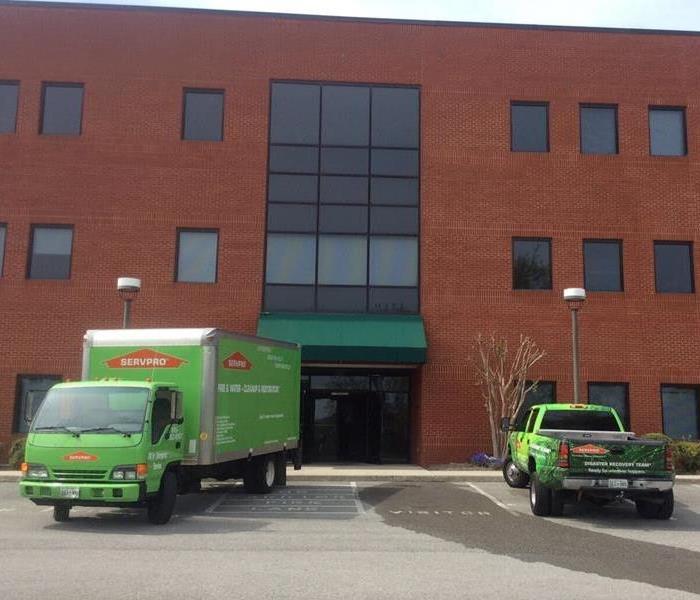 Two SERVPRO vehicles parked outside a building. 